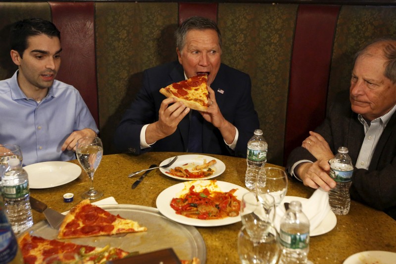 Kasich eats a slice of pizza with Ulrich and Turner at Gino's Pizzeria and Restaurant in the Queens borough of New York