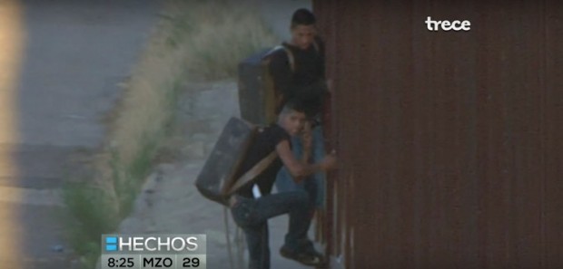 Close Up Of Smugglers Climbing Over Border Fence