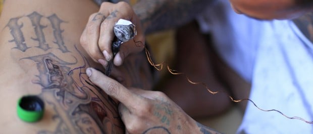 A jailed gang member gets a tattoo done by a fellow inmate at the maximum security jail of Izalco in Sonsonate