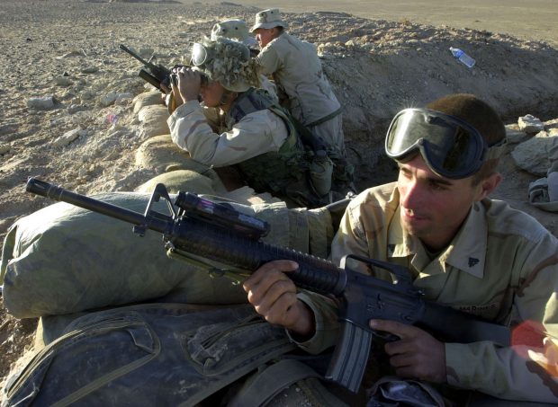 Marines man their fighting hole near Camp Rhino in Southern Afghanistan, December 9, 2001. The Marines are with Bravo Company of the 15th Marine Expeditionary Unit from Camp Pendleton, California. From left: Lance Corporal Bryce Collins of Juneau, Alaska, Corporal David Lacerte of Montegut, Louisiana, Corporal Erasmo Cantu of Baytown, Texas, and Corporal Brandon Gilkey of Huntington Beach, California. REUTERS/Dave Martin-POOL