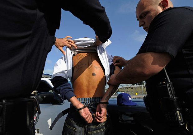 LOS ANGELES, CA - APRIL 29: Los Angeles Police Department officers from the 77th Street division detain a twenty-year old "Street Villains" gang member who was recently released from prison on April 29, 2012 in Los Angeles, California. The 77th Street division patrol the same neighborhood that truck driver Reginald Denny was nearly beaten to death by a group of black assailants at the intersection of Florence and Normandie Avenues. It?s been 20 years since the verdict was handed down in the Rodney King case that sparked infamous Los Angeles riots. (Photo by Kevork Djansezian/Getty Images)