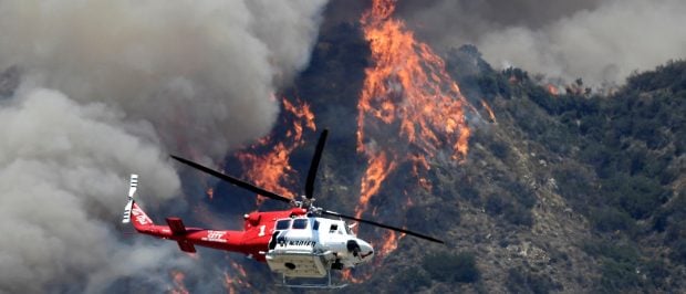 A Los Angeles City Fire Department helicopter flies over one of two wildfires in the Angeles National Forest above Azusa, California