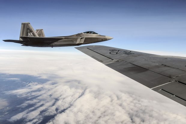 A U.S. Air Force F-22 Raptor aircraft flies alongside a KC-135 Stratotanker aircraft, foreground, during Red Flag-Alaska 13-3 over the Joint Pacific Alaska Range Complex Aug. 14, 2013. Red Flag-Alaska is a series of Pacific Air Forces commander-directed field training exercises for U.S. and partner nation forces, providing combined offensive counter-air, interdiction, close air support, and large force employment training in a simulated combat environment. (DoD photo by Senior Airman Zachary Perras, U.S. Air Force/Released)