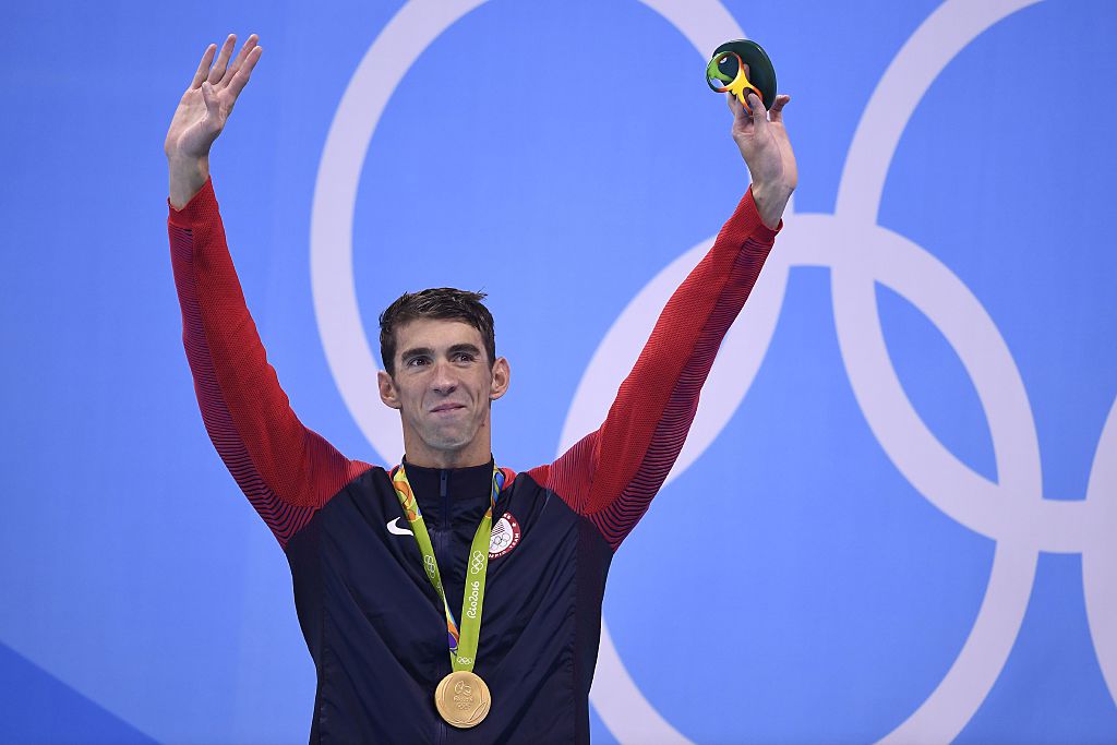 Phelps celebrates on the podium after another victory (Photo credit should read GABRIEL BOUYS/AFP/Getty Images)