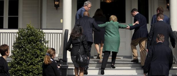 U.S. Democratic presidential candidate Hillary Clinton (in green coat, back to camera) loses her balance briefly as she arrives for a tour of SC STRONG, a home for ex-offenders and substance abusers on the grounds of the former Charleston Navy Yard in North Charleston, South Carolina February 24, 2016. REUTERS/Jonathan Ernst - RTX28EKF