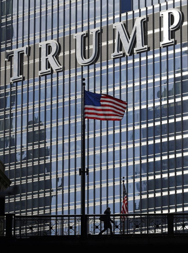 A woman crosses a bridge in front of the Trump International Hotel and Tower in Chicago