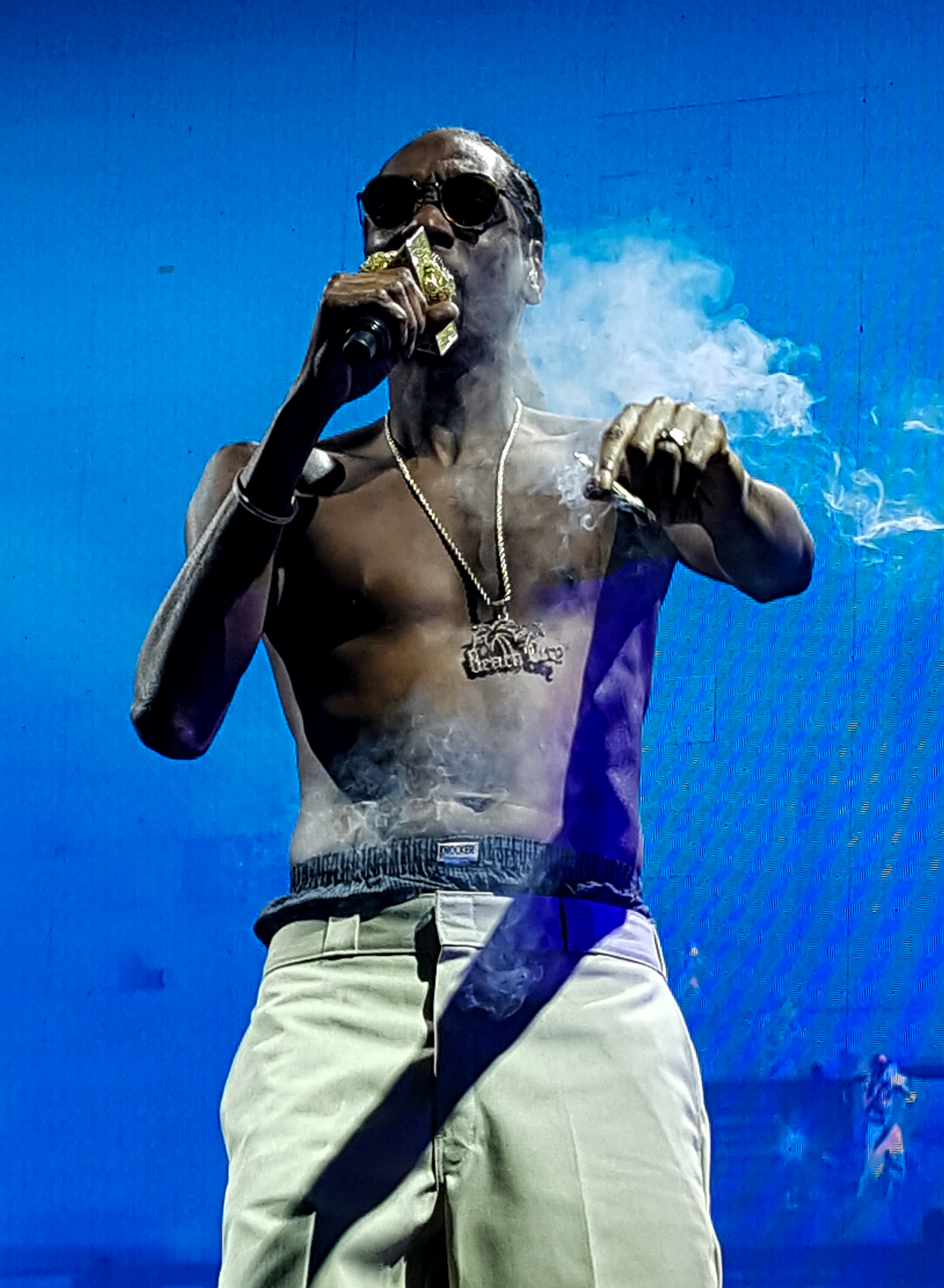 A shirtless Snoop Dogg smokes on stage on the High Road tour at Sleep Train Amphitheater in Chula Vista, CA