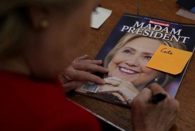 Democratic presidential nominee former Secretary of State Hillary Clinton signs an autograph on a Newsweek 'Madam President' commemerative magazine backstage after a campaign rally on November 7, 2016 in Pittsburgh, Pennsylvania. (Justin Sullivan/Getty Images)