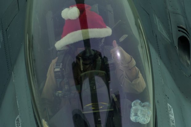 An F-16 pilots dons a red Santa hat as he refuels his aircraft mid-air. Source: Senior Airman Tyler Woodward/U.S. Department of Defense