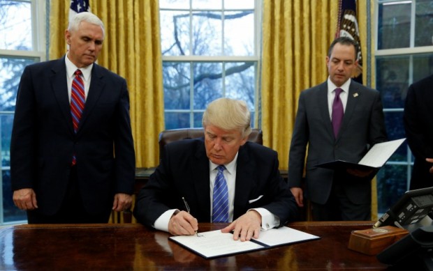 U.S. President Donald Trump signs an executive order on U.S. withdrawal from the Trans Pacific Partnership while flanked by Vice President Mike Pence (L) and White House Chief of Staff Reince Priebus (R) in the Oval Office of the White House in Washington January 23, 2017. REUTERS/Kevin Lamarque