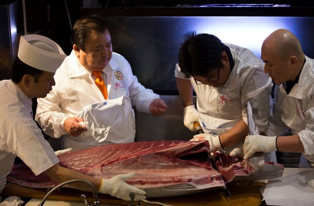 Kiyoshi Kimura, center left, looks at an employee cutting a fresh bluefin tuna on January 5, 2017. (Photo by Tomohiro Ohsumi/Getty Images)