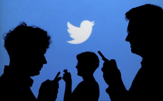 FILE PHOTO - People holding mobile phones are silhouetted against a backdrop projected with the Twitter logo in this illustration picture taken September 27, 2013. REUTERS/Kacper Pempel/Illustration/File Photo