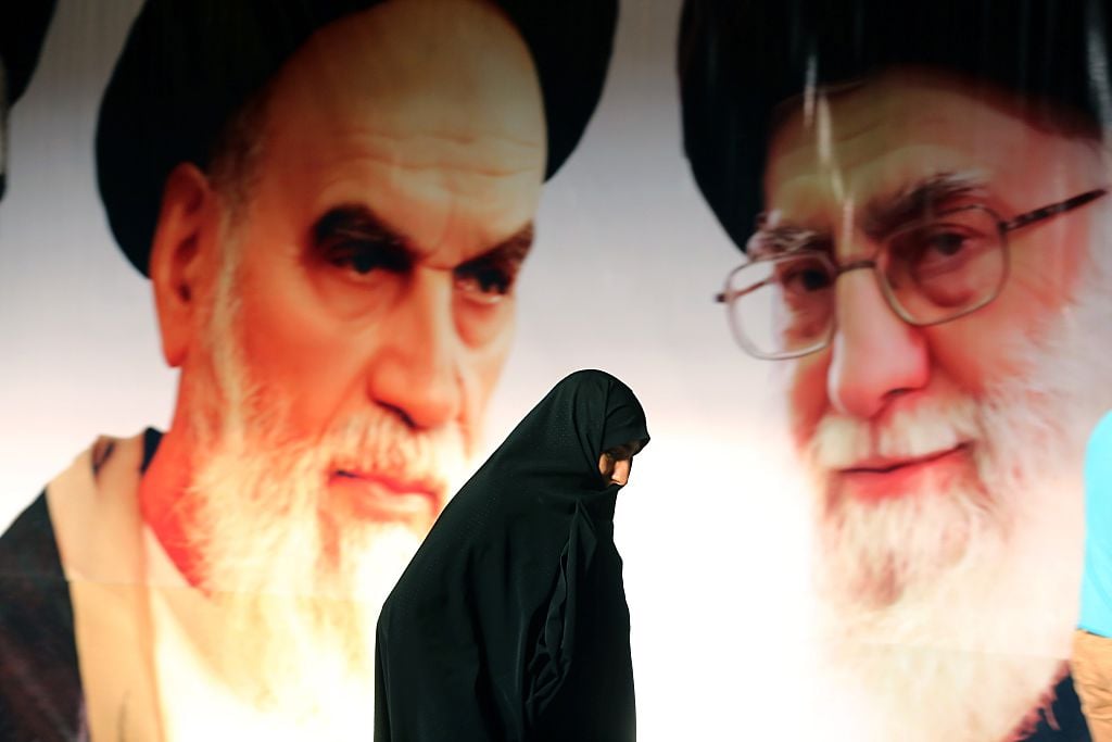 An Iranian woman walks past a giant poster showing supreme leader, Ayatollah Ali Khamenei and the founder of Iran's Islamic Republic, Ayatollah Ruhollah Khomeini (Getty Images)