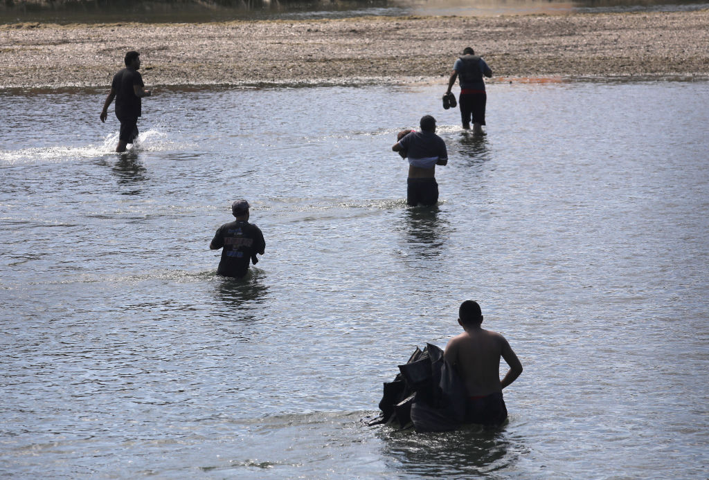 ROMA, TX - MARCH 14: A smuggler, also known as a "coyote," carries life jackets while walking a group of undocumented immigrants across the shallow Rio Grande at the U.S.-Mexico border on March 14, 2017 in Roma, Texas. U.S. Border Patrol agents intercepted them on the Texas side of the river and pushed them back into Mexico. (Photo by John Moore/Getty Images)