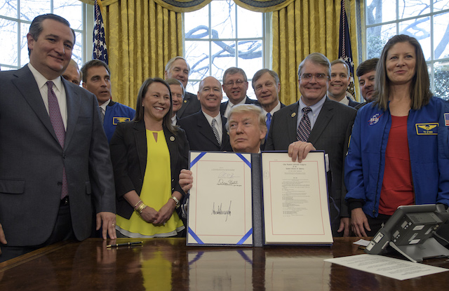 WASHINGTON, DC - MARCH 21: In this handout provided by the National Aeronautics and Space Administration (NASA), President Donald Trump, center, signs the NASA Transition Authorization Act of 2017, alongside members of the Senate, Congress, and National Aeronautics and Space Administration in the Oval Office of the White House in Washington, Tuesday, March 21, 2017. Also pictured, Sen. Ted Cruz, R-Texas, left, NASA Astronaut Office Chief Chris Cassidy, blue jacket left, Rep. John Culberson, R-Texas, right of President, NASA Astronaut Tracy Caldwell Dyson, and others. (Photo by Bill Ingalls/NASA via Getty Images)