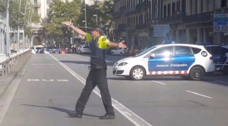 A still image from video shows a police officer gesturing while walking across a road, after a van crashed into people in the centre of Barcelona, Spain, August 17, 2017. REUTERS TV via REUTERS