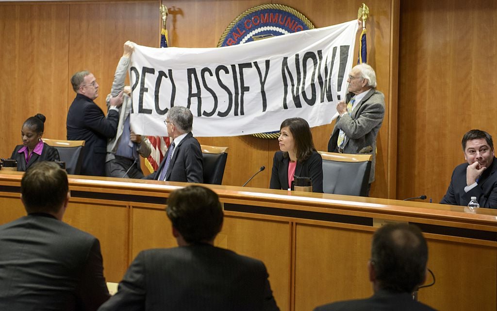 FCC commissioners watch as protesters are removed from the dais during a hearing at the agency's headquarters on December 11, 2014 in Washington, DC. The protesters were advocating for net neutrality. [Brendan Smialowski/AFP/Getty Images]