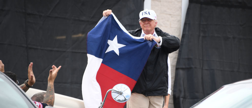 US President Donald Trump holds the state flag of Texas outside of the Annaville Fire House after attending a briefing on Hurricane Harvey in Corpus Christi, Texas on August 29, 2017. President Donald Trump flew into storm-ravaged Texas Tuesday in a show of solidarity and leadership in the face of the deadly devastation wrought by Harvey -- as the battered US Gulf Coast braces for even more torrential rain. JIM WATSON/AFP/Getty Images