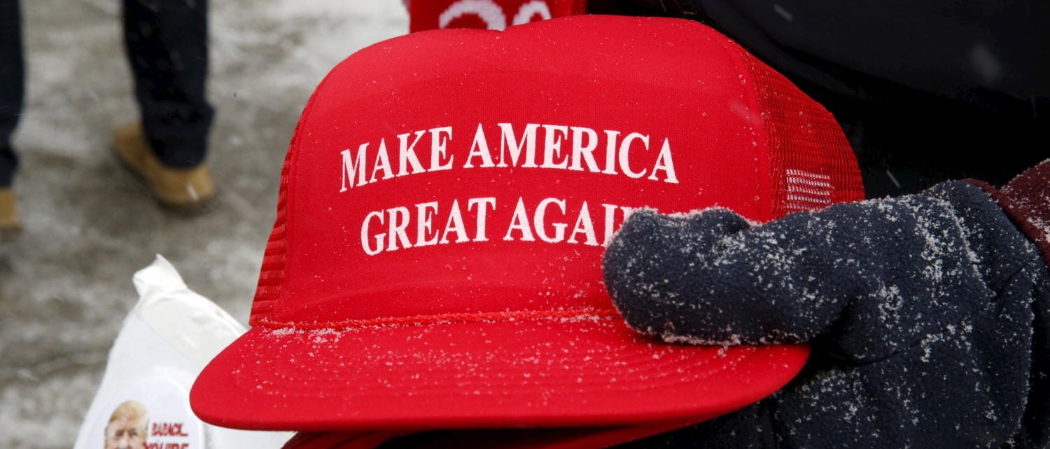 Trump campaign merchandise vendor David Dickson from Florida holds Trump campaign "Make America Great Again" hats dusted with falling snow outside a Trump campaign town hall event in Londonderry, New Hampshire February 8, 2016. REUTERS/Jim Bourg - GF10000301111