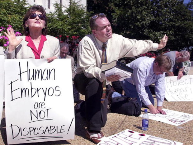 WASHINGTON, DC - SEPTEMBER 6: Rev. Flip Benham of Dallas, Texas, (C) a member of the Christian Defense Coalition prays with Eva Edl of Aiken, South Carolina (L) and Rev. Cal Zastro (R) as they gather in front of a senate office building on Capitol Hill, 06 September 2001 to protest US President George W. Bush's decision to allow limited stem cell research. The protestors plan demonstrations at Washington hospitals and government offices. (Photo credit should read MIKE THEILER/AFP/Getty Images)