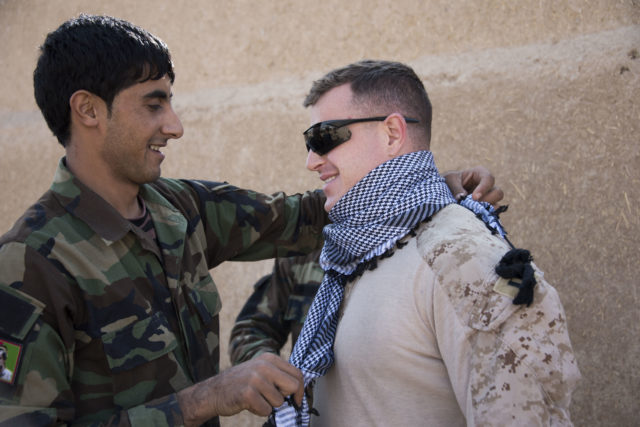 Capt. Richard Laszok receives a lesson on scarf-tying from a soldier in the Afghan National Army's 6th Kandak, 1st Brigade. The scar was a gift from Afghan Lt. Col. Mohibula (2nd Kandak, 4th Brigade Commander) who completed training at the Helmand Regional Training Center over the summer. (Hailey Sadler)