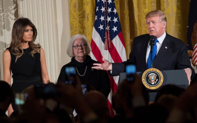 US President Donald Trump speaks alongside First Lady Melania Trump (L), and Holocaust survivor Louise Lawrence-Israels (C) during a Hanukkah reception in the East Room of the White House in Washington, DC, December 7, 2017. / AFP PHOTO / SAUL LOEB