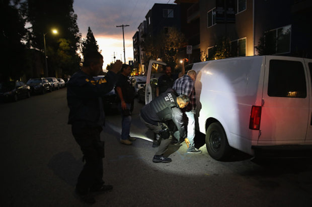 LOS ANGELES, CA - OCTOBER 14: A man is detained by Immigration and Customs Enforcement (ICE), agents early on October 14, 2015 in Los Angeles, California. ICE agents said the undocumented immigrant was a convicted criminal and gang member who had previously been deported to Mexico and would be again. ICE builds deportation cases against thousands of undocumented immigrants, most of whom, they say, have criminal records. The number of ICE detentions and deportations from California has dropped since the state passed the Trust Act in October 2013, which set limits on California law enforcement cooperation with federal immigration authorities. (Photo by John Moore/Getty Images)