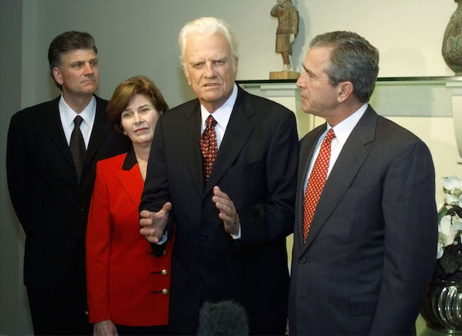 Rev. Billy Graham praises Republican presidential candidate George W. Bush in a meeting with press in Jacksonville, Florida, November 5, 2000. Billy Graham's son Franklin and Laura Bush look on. REUTERS