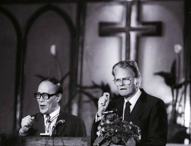 As American evangelist Billy Graham preaches to the congregation at Chongwenmen church Sunday, April 17, 1988, his words and gestures along with their fervor are translated into Chinese by Philip Teng. It was Graham's first visit to China. REUTERS/Edward Nachtrieb