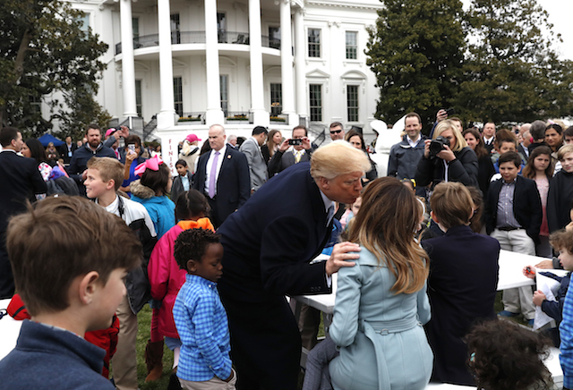 U.S. President Donald Trump kisses first lady Melania Trump among children gathered for the annual White House Easter Egg Roll on the South Lawn of the White House in Washington, U.S., April 2, 2018. REUTERS/Leah Millis - HP1EE42160RPW