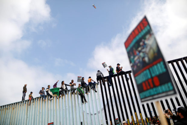 Members of a caravan of migrants from Central America and activists sit on the border fence between Mexico and the U.S., as a part of a demonstration prior to preparations for an asylum request in the U.S., in Tijuana, Mexico April 29, 2018. REUTERS/Edgard Garrido