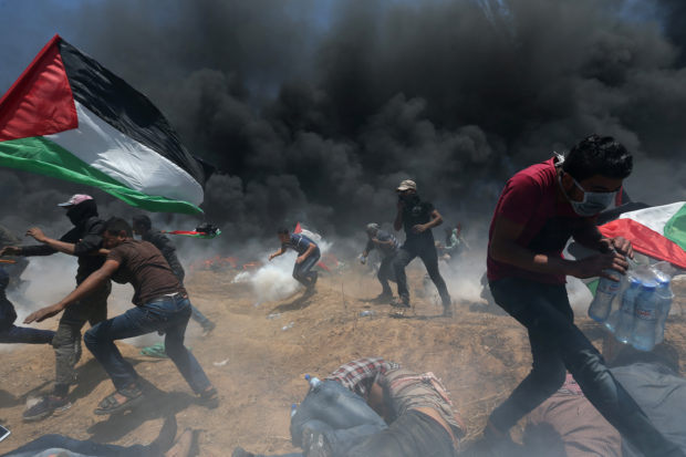 Palestinian demonstrators run for cover from Israeli fire and tear gas during a protest against U.S. embassy move to Jerusalem and ahead of the 70th anniversary of Nakba, at the Israel-Gaza border in the southern Gaza Strip May 14, 2018. REUTERS/Ibraheem Abu Mustafa