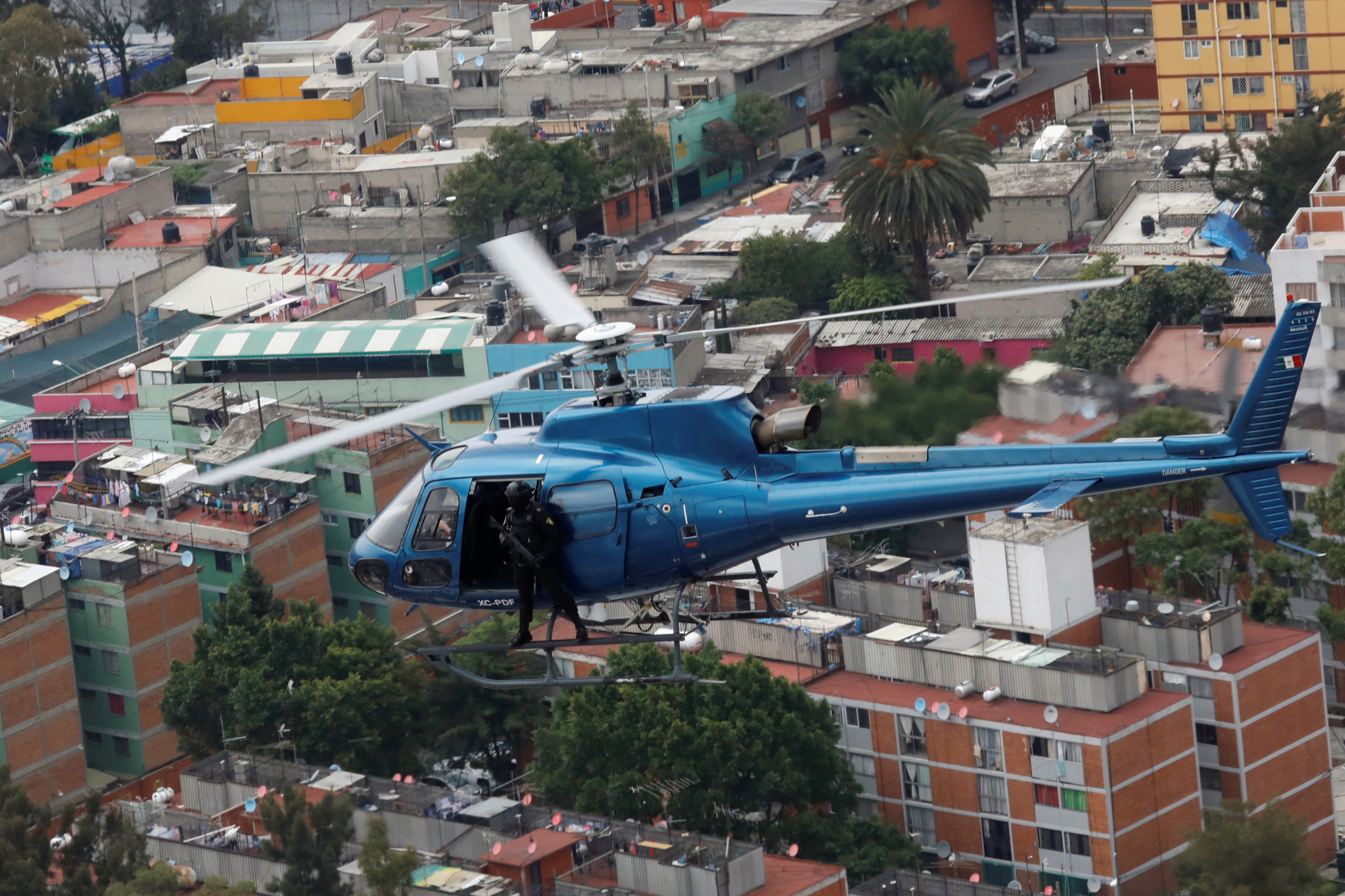 Police officers, members of a team known as "Condores", stand by the door of the helicopter during a patrol of the city, part of a new strategy to combat the crime in Mexico City, Mexico August 3, 2018. Picture taken August 3, 2018. REUTERS/Carlos Jasso - RC1ADE095290
